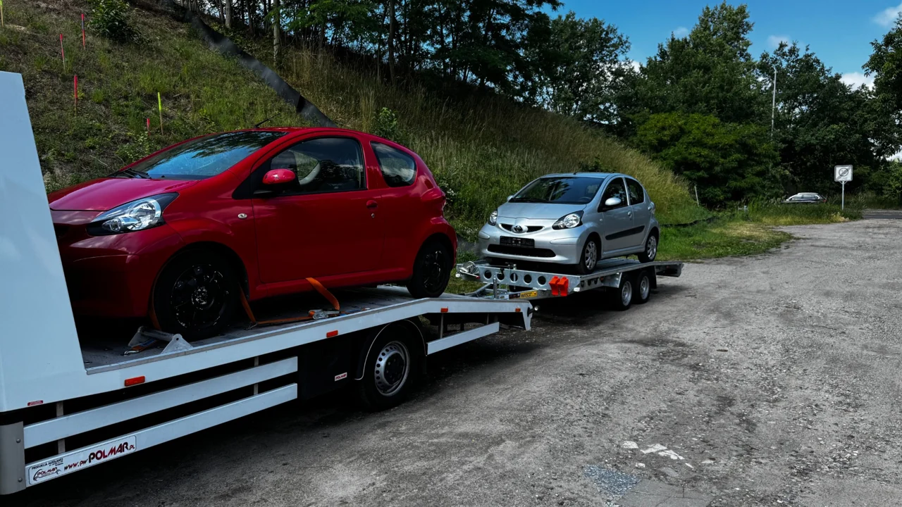 Dwa samochody przewożone na autolawecie z przyczepą